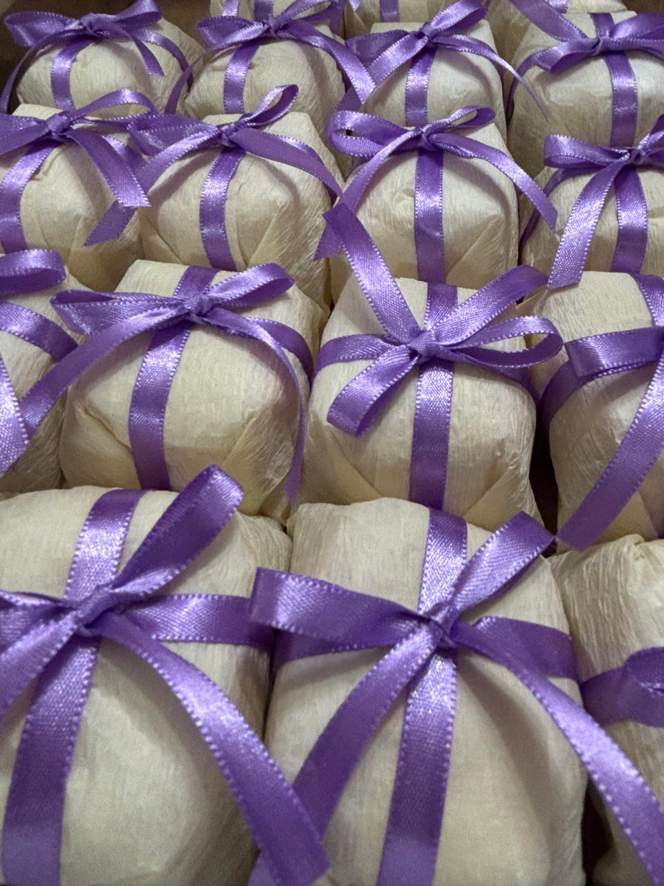 Bem casados embalados em papel creme com laço de fita de cetim lilás