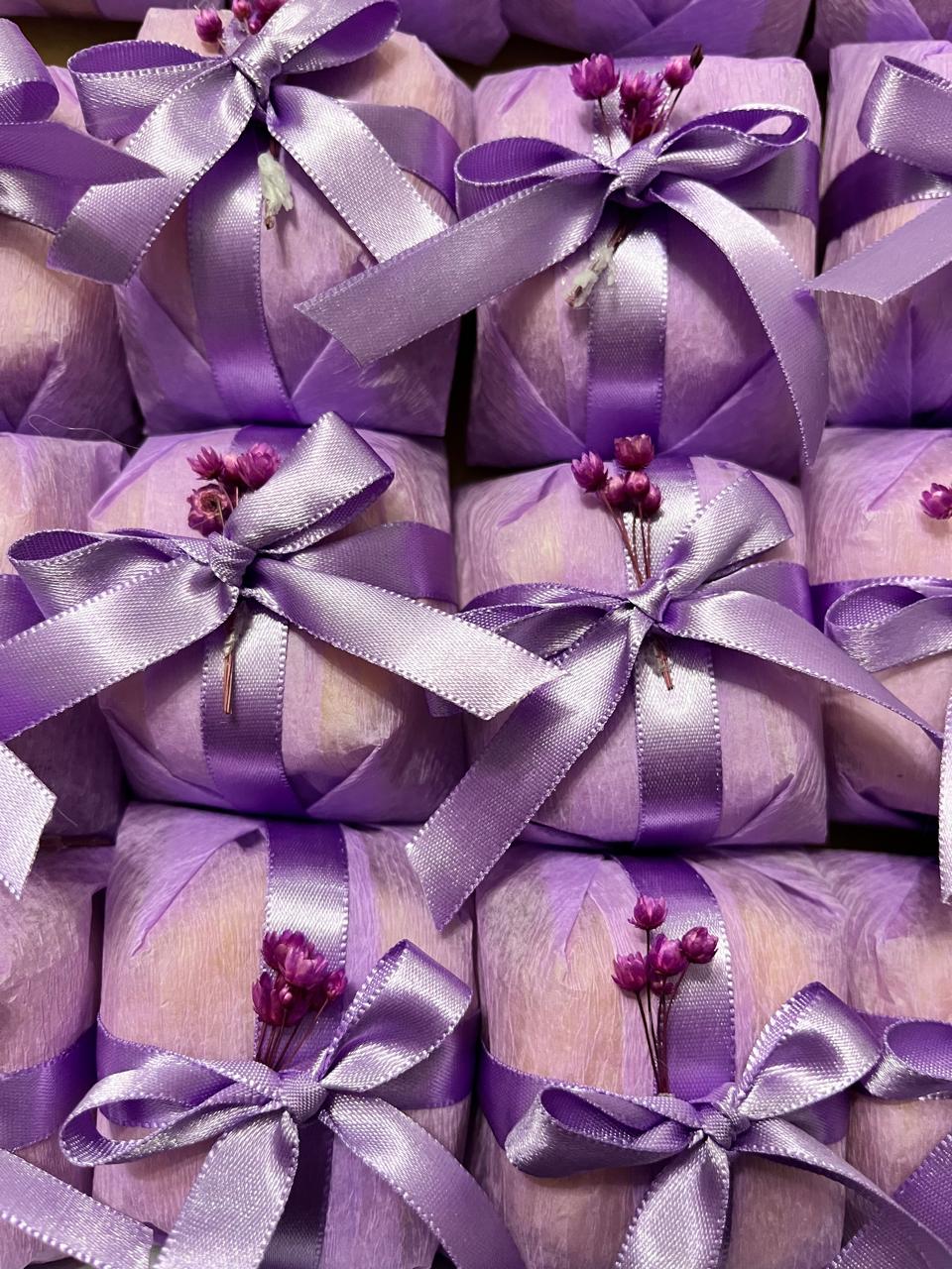 Bem casados embalados em papel lilás com laço de cetim lilás e aplique de flores secas