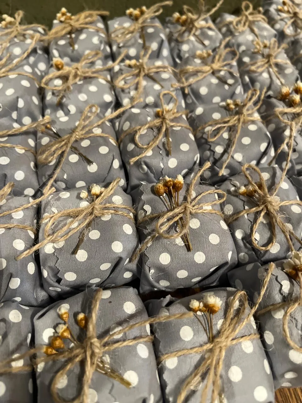 Bem casados embalados em papel cinza com poá branco, amarrados com cordão de juta e mini flores secas