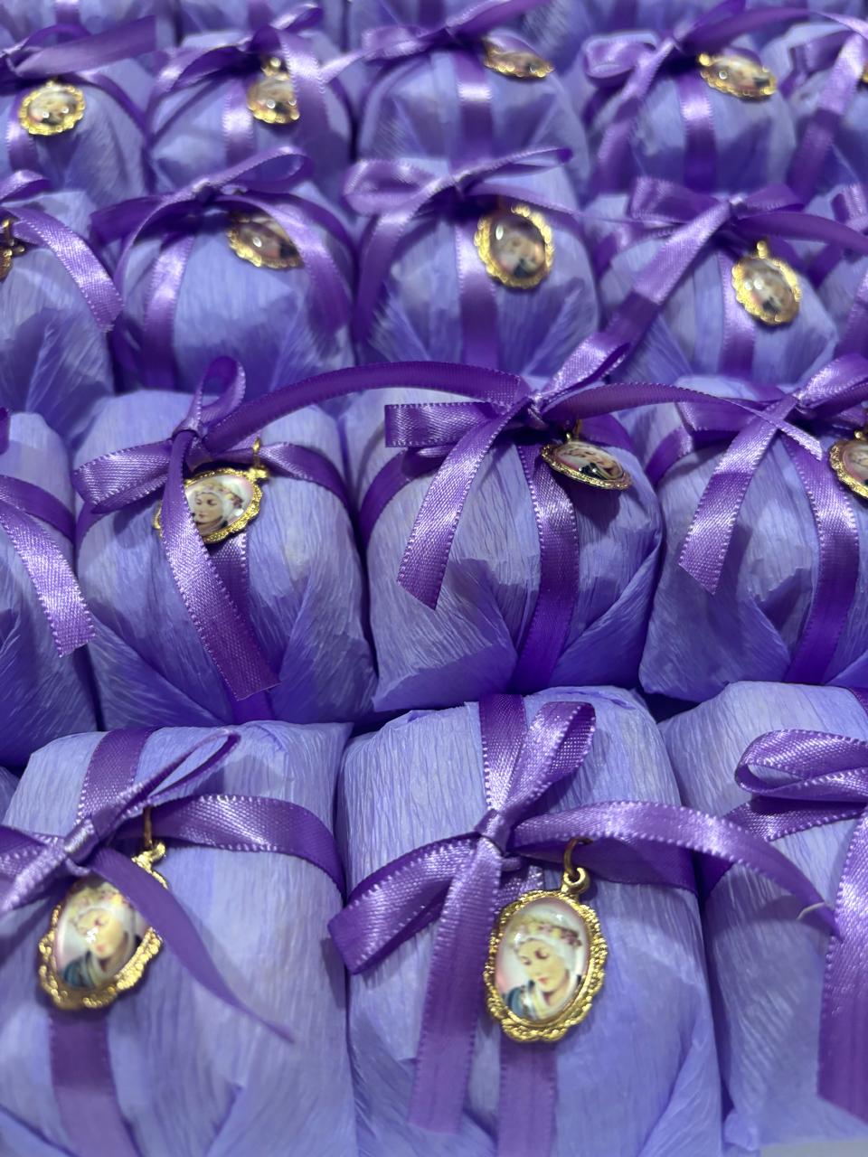 Bem casados embalados em papel lilás com laço roxo e medalha dourada