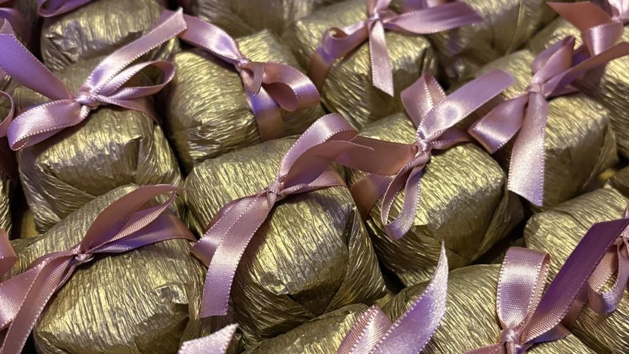 Bem casados embalados em papel dourado com laço de cetim rosê, para presentes de empresa