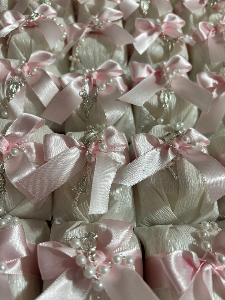 Bem casados embalados em papel branco com laço rosa claro e mini terço de pérolas com crucifixo