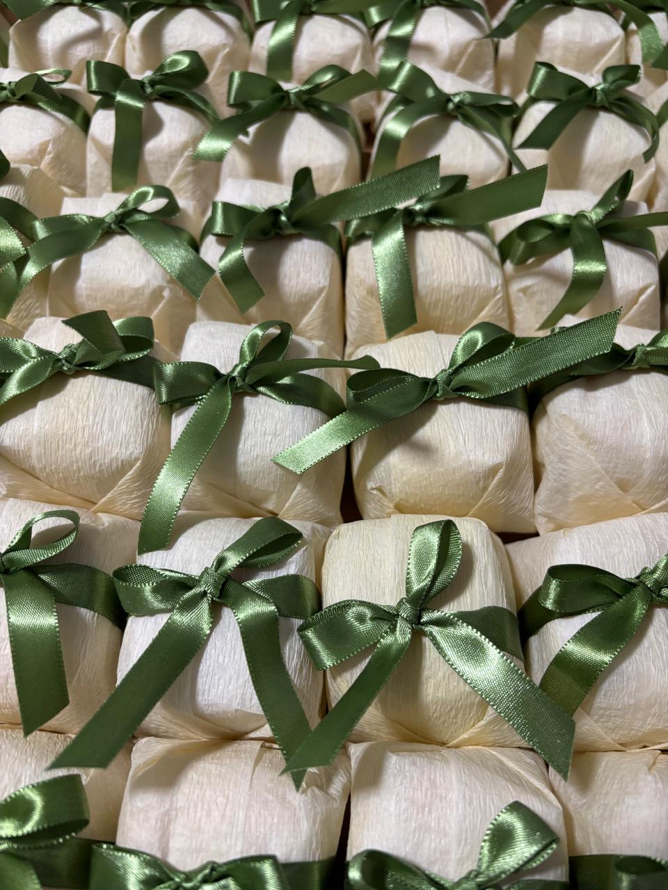 Bem casados embalados em papel creme com fita e laço de cetim verde-oliva
