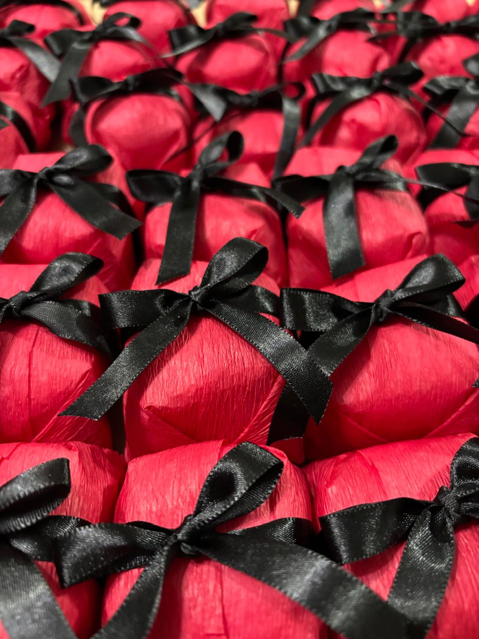 Bem casados embalados em papel vermelho com fita e laço de cetim preto