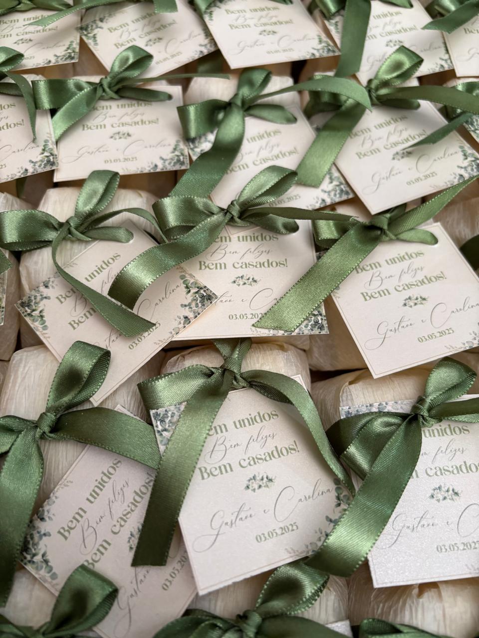 Bem casados embalados em papel creme com laço verde-oliva e tag personalizada com nomes e data do casamento