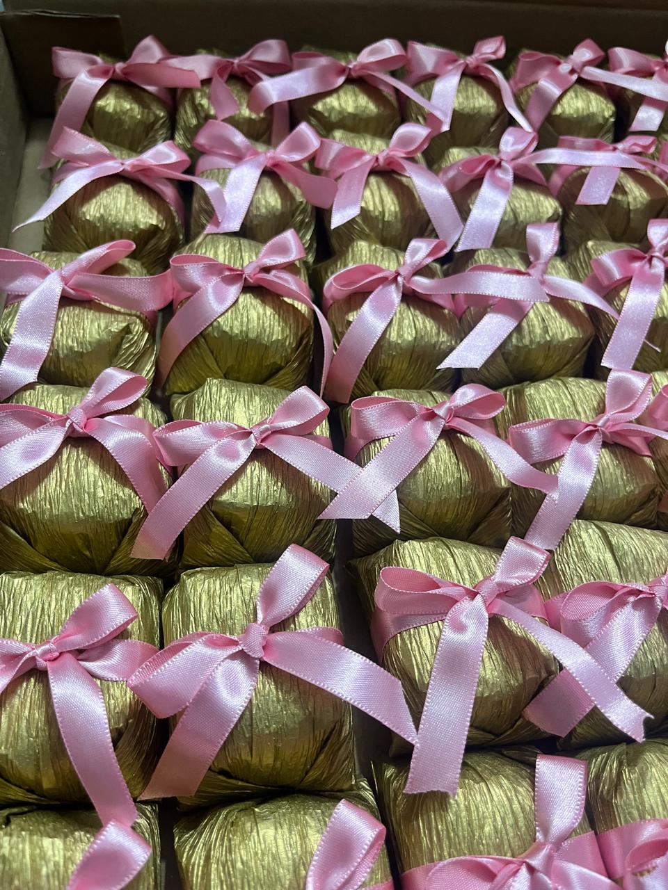 Bem casados em tons dourado e rosa claro, organizados em caixa com fita e laço de cetim rosa claro