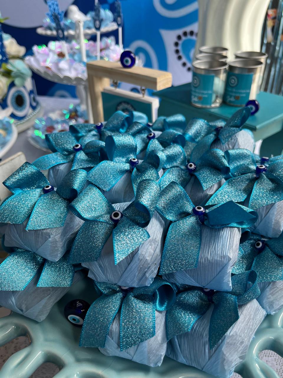 Bem casados embalados em azul-turquesa brilhante com laço azul e aplique de olho grego