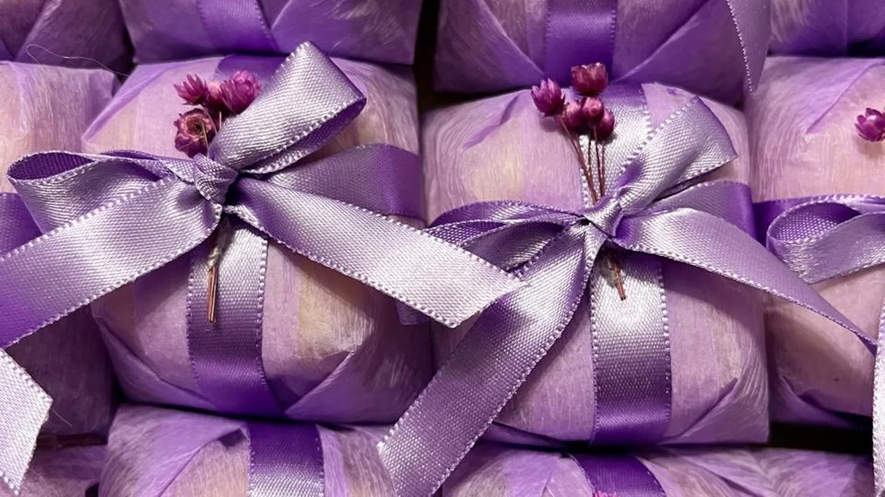 Bem casados personalizados em papel lilás com laço de cetim lilás e aplique de flores secas