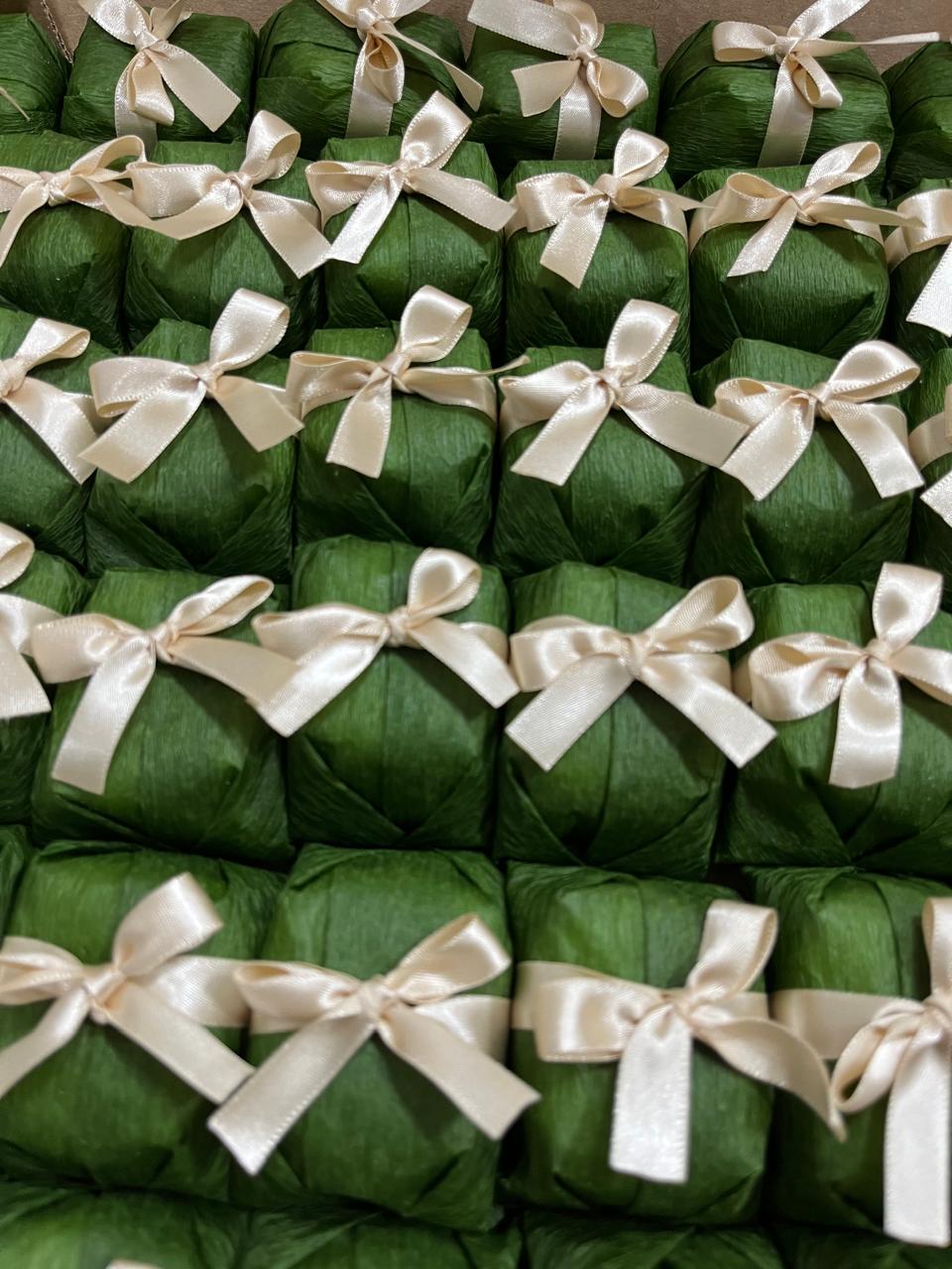 Bem casados embalados em papel verde-escuro com laço de cetim champanhe