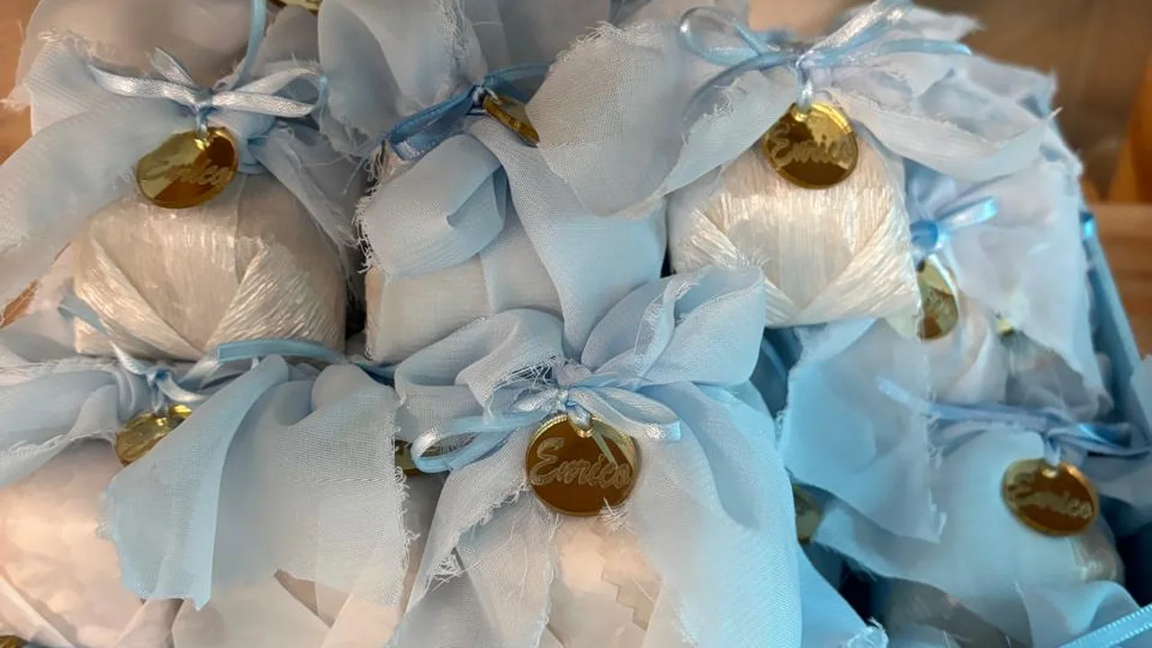 Bem nascidos embalados em azul-bebê e branco, com laço de tecido rústico e tag dourada