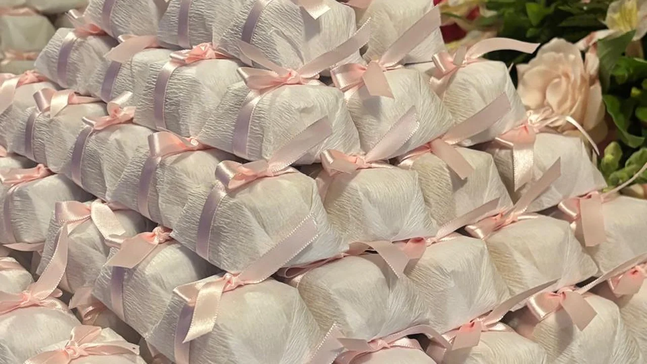 Bem casados embalados em papel branco, empilhados em pirâmide com fita e laço de cetim rosa claro