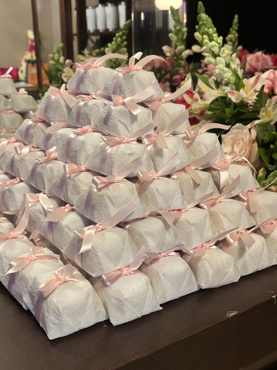 Bem casados embalados em papel branco, empilhados em pirâmide com fita e laço de cetim rosa claro